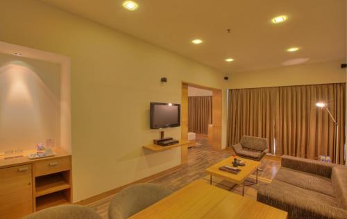 a living room with a couch and a tv at Hotel Parc Estique in Pune