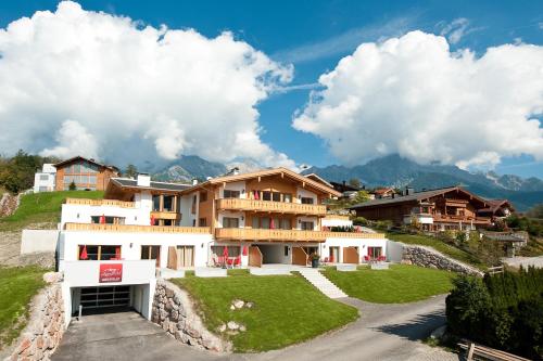 a building on a hill with mountains in the background at AlpenParks Apartments Maria Alm in Maria Alm am Steinernen Meer
