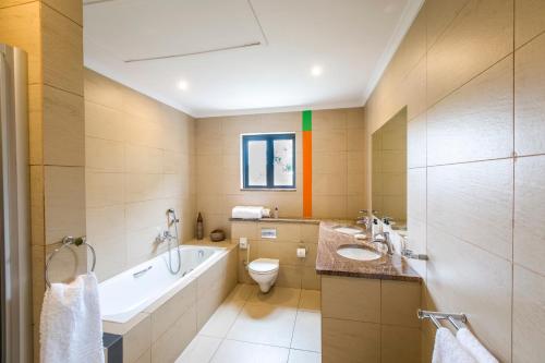 a bathroom with a tub and a toilet and a sink at Orange Inn Knysna in Knysna