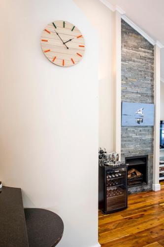 a clock on a wall in a living room with a fireplace at Orange Inn Knysna in Knysna