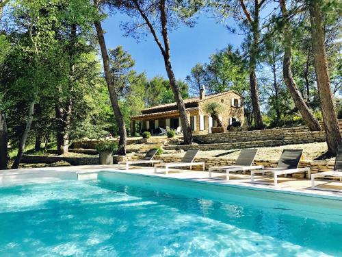 a pool with chairs and a house in the background at Zen et Chic in Ménerbes