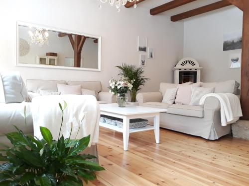 una sala de estar con 2 sofás blancos y una mesa. en Ferienhaus Rosenhof, en Weidenbach