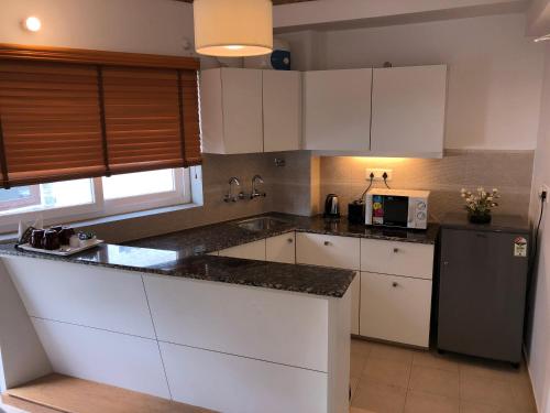 a kitchen with white cabinets and a black refrigerator at The Pinewood, Nainital by Leisure Hotels in Nainital