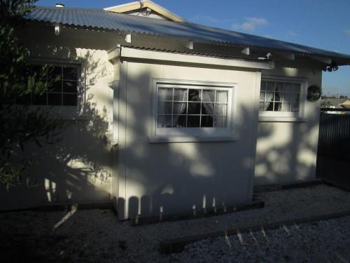 a white house with two windows on the side of it at Monday Seaside Cottage in Whanganui