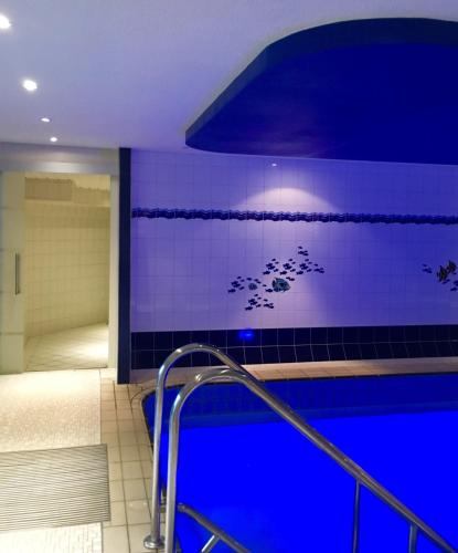 a bathroom with a swimming pool with blue lighting at Landhotel Hubertus in Unterelsbach