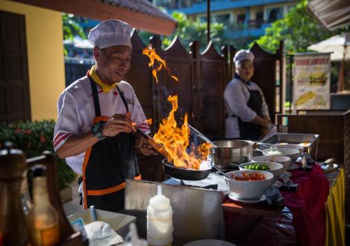un homme cuisinant de la nourriture dans un pot sur un grill dans l'établissement Karona Resort & Spa - SHA Extra Plus, à Karon Beach