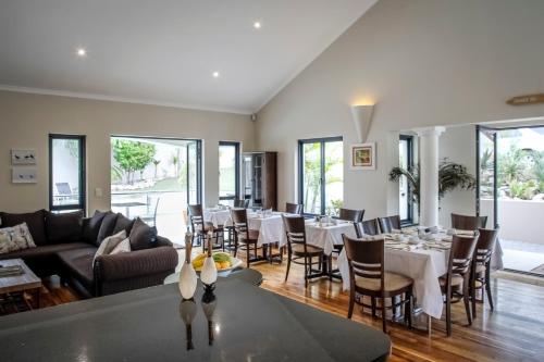 a dining room with white tables and chairs at Orange Inn Knysna in Knysna