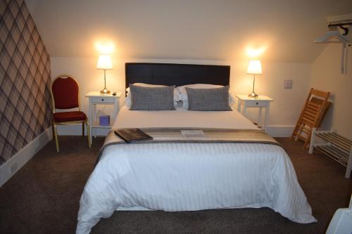 a bedroom with a large bed with two chairs and two lamps at The Tables Guest House in Dunvegan
