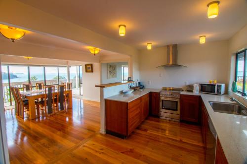 cocina con suelo de madera y mesa con sillas en Orewa Cliff Top, en Orewa