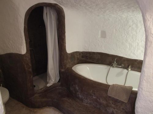 a bathroom with a wooden tub and a toilet at Cueva Las Yeseras in Baza