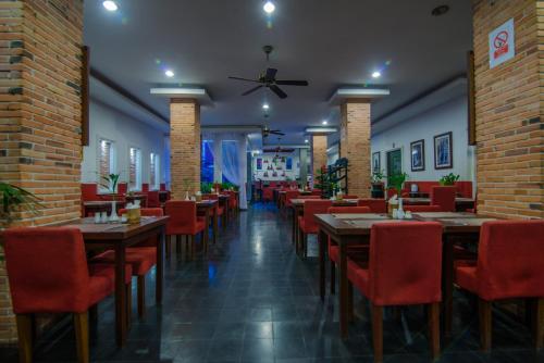 a restaurant with wooden tables and red chairs at Mekong Angkor Deluxe Hotel in Siem Reap