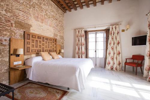 a bedroom with a bed and a brick wall at Hotel Casa de las Cuatro Torres in Cádiz