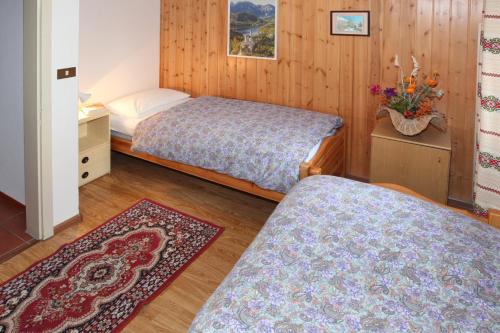 een slaapkamer met 2 bedden en een tapijt bij Casa De Biasio PM in Falcade