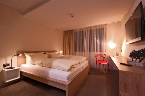 a hotel room with a bed and a red chair at Hotel Credé in Kassel