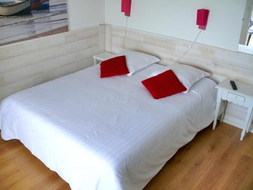 a white bed with two red pillows on it at Hôtel Le Vivier WISSANT - Vue Mer - Côte d'Opale - Baie de Wissant - 2CAPS in Wissant