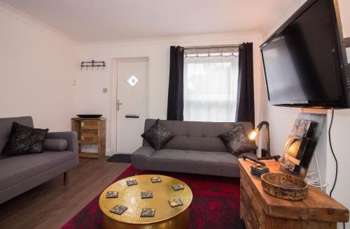 a living room with a couch and a flat screen tv at Magdalen Quarters in Exeter