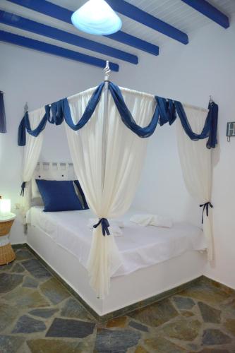a bedroom with a white bed with blue curtains at Traditional Villa Relax in Zefiría