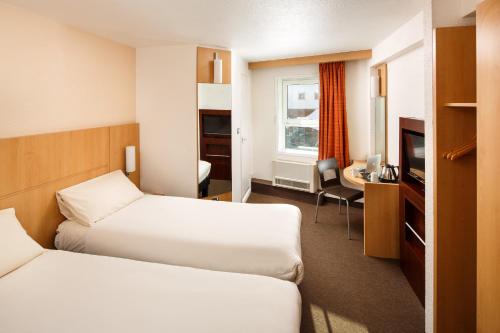 a hotel room with two beds and a television at ibis Birmingham Centre New Street Station Hotel in Birmingham