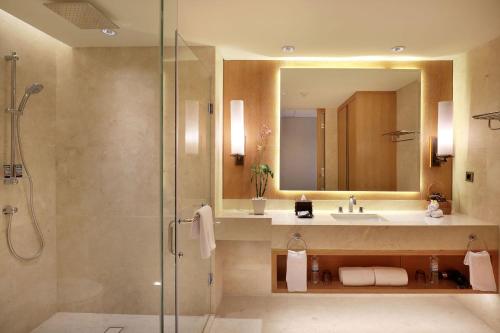 a bathroom with a shower and a sink and a mirror at Aryaduta Bali in Kuta