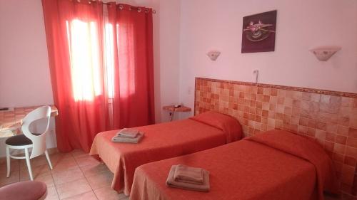 a hotel room with two beds and red curtains at Hotel des Etrangers in Bonifacio