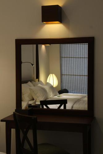 a mirror in a room with a bed and a table at Coza Ceylon in Mount Lavinia