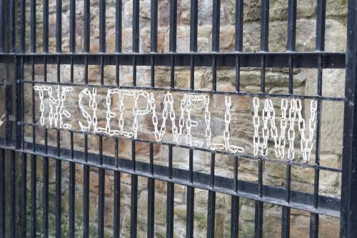 a metal fence with graffiti on the side of it at The Sleepwell Inn in Workington