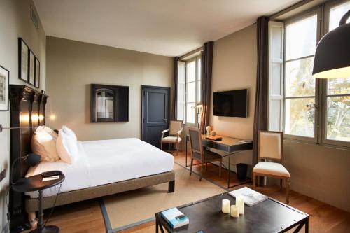 a bedroom with a bed and a desk and a room at Domaine de Fontenille in Lauris