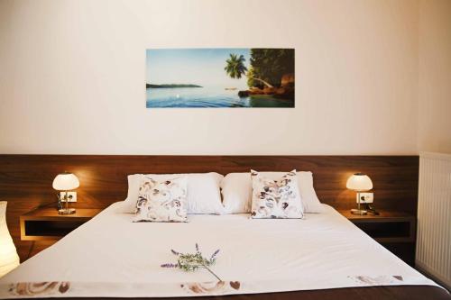ein Schlafzimmer mit einem Bett mit zwei Lampen und einem Gemälde in der Unterkunft Apartments Visnja in Vodice