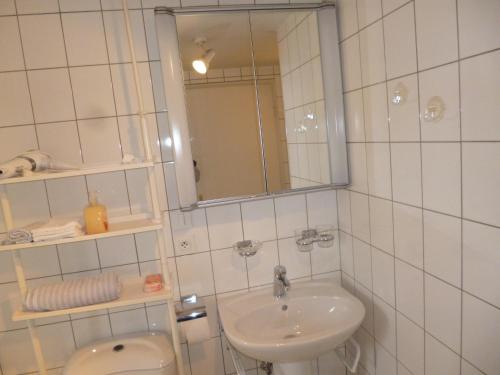 ein weiß gefliestes Bad mit einem Waschbecken und einem Spiegel in der Unterkunft Albrecht guest apartement in Kembs