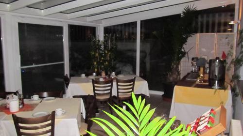 a dining room with white tables and chairs and windows at Park Hotel Gastein inklusive 1x Badesee und alle Getränke ganztags inklusive in Bad Hofgastein