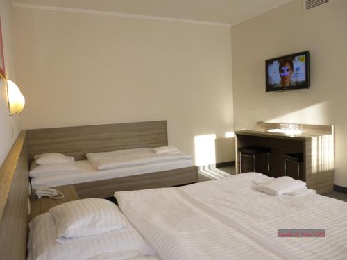 a hotel room with two beds and a desk at Paprika M1 Hotel in Hegyeshalom