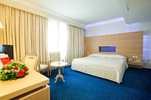 a hotel room with a bedroom with a bed and a desk at El Mouradi Mahdia in Mahdia