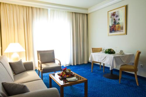 a hotel room with a table and chairs and a room at El Mouradi Mahdia in Mahdia