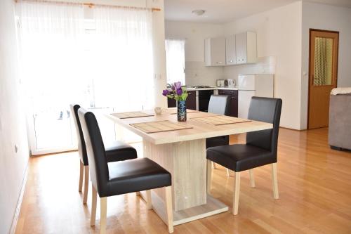 a dining room table with black chairs and a kitchen at Family house Branka with SPA pool in Peroj