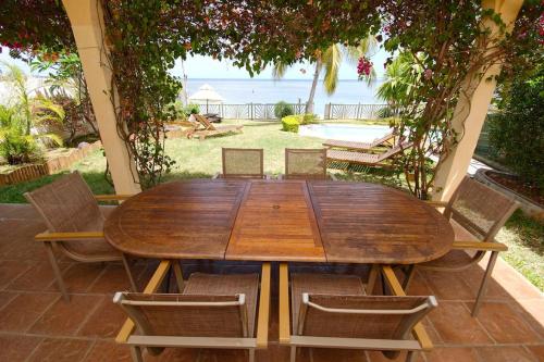 a wooden table and chairs with a view of the ocean at Villa Mauridul in Baie du Tombeau