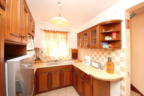 a kitchen with wooden cabinets and a sink at Villa Mauridul in Baie du Tombeau