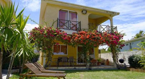 a yellow house with flowers in front of it at Villa Mauridul in Baie du Tombeau