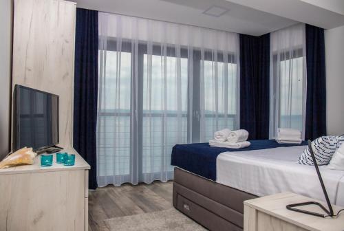 a bedroom with a bed and a tv and windows at Apartment Di Blu in Novi Vinodolski