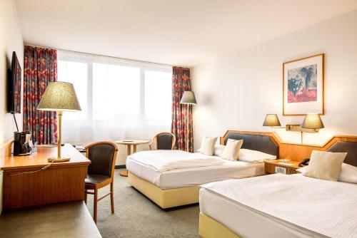 ルートヴィヒスハーフェン・アム・ラインにあるLeoso Hotel Ludwigshafenのベッド2台とデスクが備わるホテルルームです。