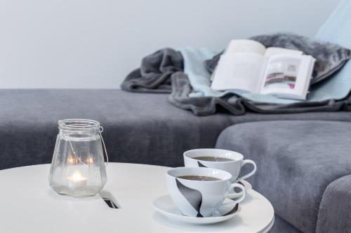 two cups of coffee on a table next to a couch at Elite Apartments Oliwa Business Center in Gdańsk