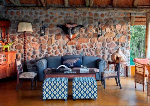 a living room with a blue couch and a stone wall at Geiger's Camp in Timbavati Game Reserve by NEWMARK in Timbavati Game Reserve