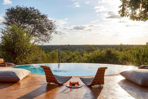 a swimming pool with two chairs and a table at Geiger's Camp in Timbavati Game Reserve by NEWMARK in Timbavati Game Reserve