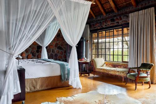 a bedroom with a bed and a chair and a window at Geiger's Camp by NEWMARK in Timbavati Game Reserve