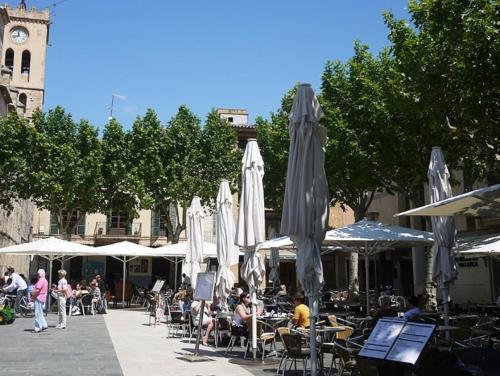 a group of people sitting at tables with umbrellas at Calvari in Pollença