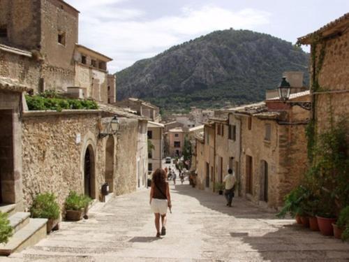 a woman walking down a street in an alley at Calvari in Pollença