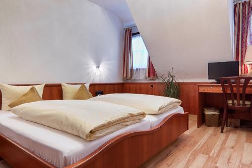 a bedroom with a bed and a desk with a television at Hotel Lamm in Weinstadt