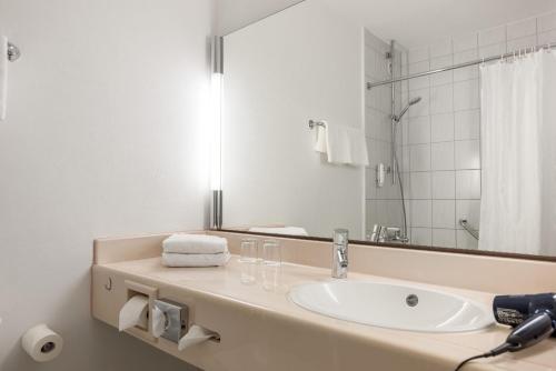 W łazience znajduje się umywalka i lustro. w obiekcie Leoso Hotel Ludwigshafen w mieście Ludwigshafen am Rhein