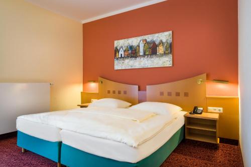 ein Schlafzimmer mit einem großen Bett und einer orangefarbenen Wand in der Unterkunft Mercure Hotel Ingolstadt in Ingolstadt
