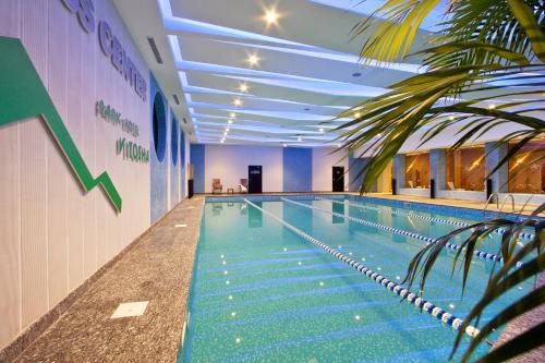 a large swimming pool in a building with a palm tree at Vitosha Park Hotel - Free Indoor Pool & Parking in Sofia