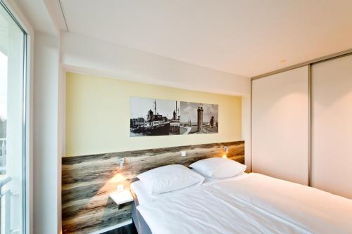 クックスハーフェンにあるDuhner Strandhusのベッドルーム1室(壁に絵が描かれた白いベッド1台付)